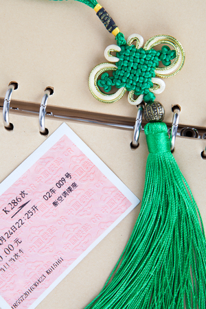 Train tickets on a brown notebook page with a Chinese traditional knotのeditorial素材
