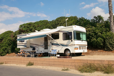 A man and his dog enjoying the shade of their trailer on a beautiful sunny day in the parking lot for RVs in Faria Beach National Park in Ventura County, CA. USESのeditorial素材