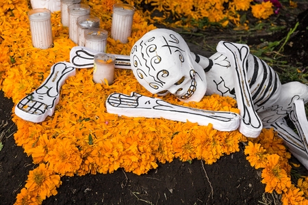 A cardboard skull rests on a bed of petals of sempazuchil flowers and candles still unlit. This type of crafts are made with wire, paper and glue, and decorated with paint and all kinds of colorful and eye-catching materials. Detail of one of many scenogrのeditorial素材