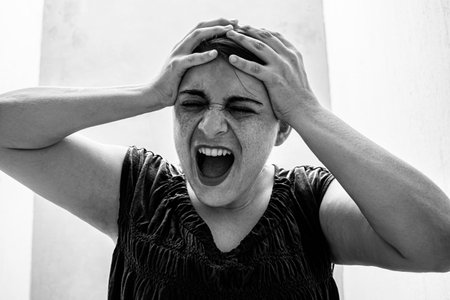 Desperate screaming woman with hands on her headの写真素材