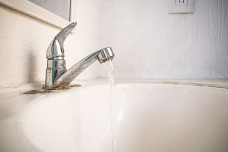 Water faucet open, pouring water into the sink.の写真素材