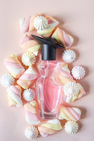 perfume bottle with sweet colored marshmallows on a pink background. sweet composition