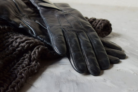 women's black leather gloves on a knitted scarf. business conceptの写真素材