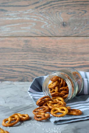 fresh pretzels with sea salt fall out of the jar vertical photo. back wooden background gray napkinの写真素材