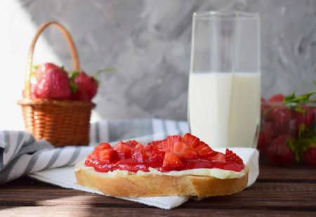 sweet sandwich with butter strawberry jam and pieces of fresh strawberries a glass of fresh cows milkの写真素材