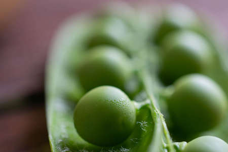 Green pea fruits on a wooden surface close-up, soft focus. sweet fruit peasの写真素材