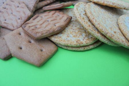 various kinds of biscuit cookies, round with bran, chocolate rhombic lies on a green background