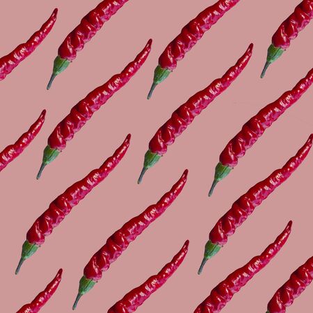 many red thin fresh bitter peppers on a pink backgroundの写真素材