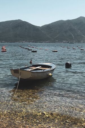 old fishing boat tied with rope on the shore of the bay against the backdrop of dark mountains
