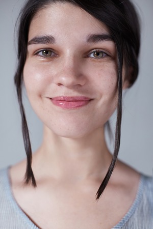 lovely beautiful young girl pulls a strand of hair, she looks at the frame, the picture is made in a light gray scaleの写真素材