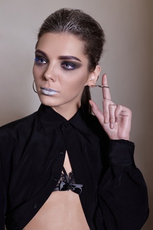 pretty girl posing in front of the camera, she has a dark make-up and a black open shirtの写真素材