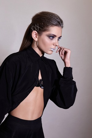 pretty girl posing in front of the camera, she has a dark make-up and a black open shirtの写真素材