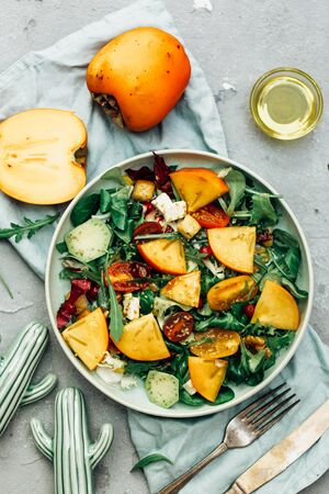 healthy delicious winter salad with persimmon slices, mix of spinach, arugula and lettuce leaves with blue cheese and walnuts の写真素材