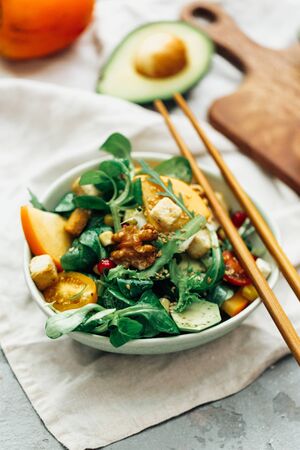 Healthy salad with persimmon, arugula, nuts and feta cheese. Fitness food. Superfoods Vitamin autumn persimmon salad.の写真素材