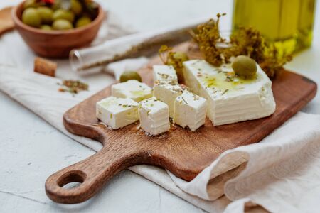 Fresh Greek Feta Cheese with olives. Healthy ingredient for cooking salad. Chopped Goat feta cheese on cutting board.の写真素材