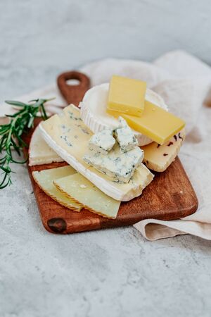 Different sorts of cheese, blue, brie, camembert and other with walnuts on wooden board backgroundの写真素材