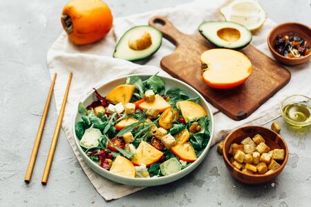 healthy delicious winter salad with persimmon slices, mix of spinach, arugula and lettuce leaves with blue cheese and walnuts の写真素材