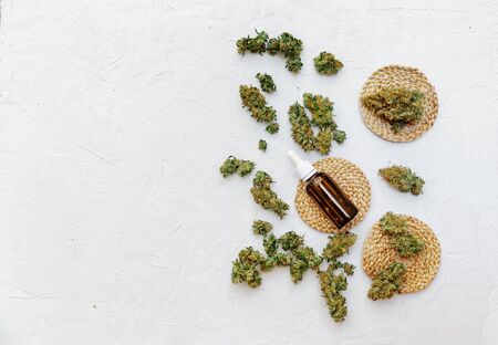 Top view of medical marijuana buds near bottles with hemp oil on white background. Detail of cannabis bud (crimson strain) - medical marijuana conceptの写真素材