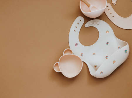 Cute baby bib for food on brown light background, top view, copy space, Bright baby tableware and bib, kid first foodの写真素材