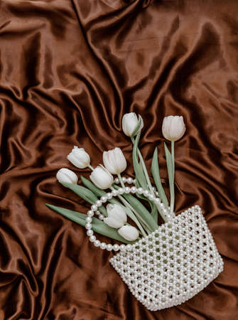 Bouquet white tulips in pearl bag. Elegant glamor fashion concept for woman day. Top view, flat lay, copy spaceの写真素材