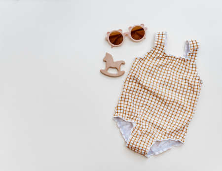 Summer kid's vacation concept - swimsuit and sun glasses on neutral background above flat layの写真素材