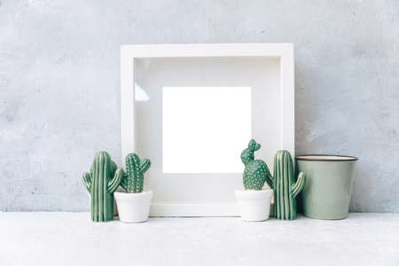 Minimal Mock up white frame with ceramic cactus plants in pots on a shelf or desk. White shelf and wall.の写真素材