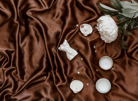 Woman candle. Aroma candle in the shape of a female body on elegant silky background. Minimalistic backgroundの写真素材