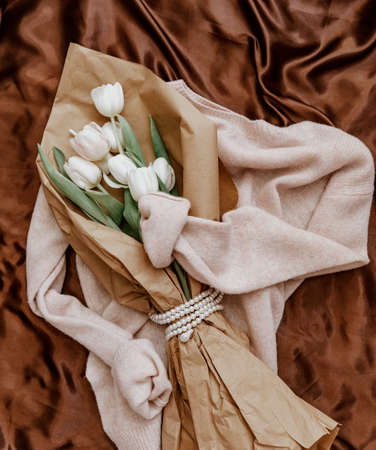 Bouquet of white tulips on a knitted sweater, top view, bouquet of tulips for women's day, concept of spring flowers.の写真素材