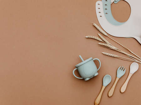 Set with bright baby dishware on table, silicone set on a trendy brown background, flat lay. Serving baby food.の写真素材
