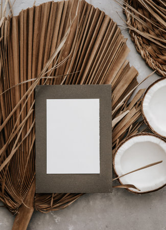 Creative flat lay top view of dry tropical palm leaves, coconut and blank card. Minimal tropical palm leaf plants summer concept template for your text or designの写真素材