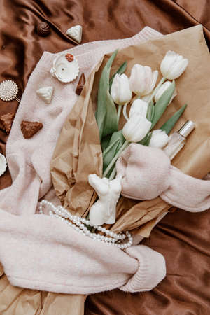 Bouquet of white tulips on a knitted sweater, top view, bouquet of tulips for women's day, concept of spring flowers. Cozy soft backgroundの写真素材
