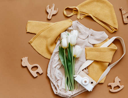 Summer baby clothes on white background, fashion newborn concept, neutral bodysuit with tulips and eco friendly toys. Top viewの写真素材