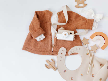 Top view baby girl fashion cloths with tulips. Wooden toys and newborn staff on white background