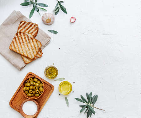 Green olives, olive oil and ciabatta bread. Top view flat lay with copy space