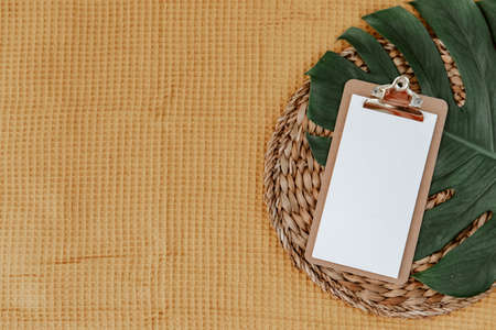 Flat lay clipboard and monstera leaf. Minimal planning background, goals, space for text