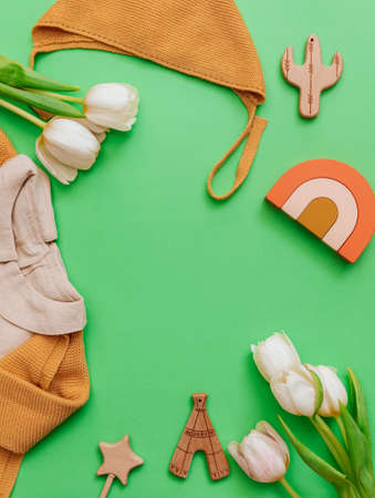 Set of baby items and accessories on green background. Wooden toys and tulips flat lay. Blogger...