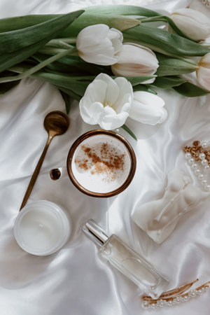 Female spring background, still life composition with coffee cup, candle, tulips, and woman accessory on silk background. womens holiday. Mothers Day. Womens Day.の写真素材