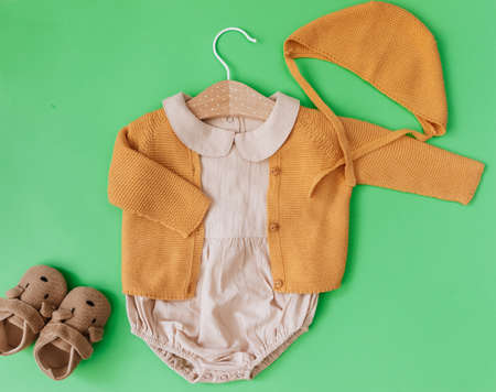 Flat Lay Newborn Trendy Background. Fashion look baby girl clothes and toy with tulips over green...