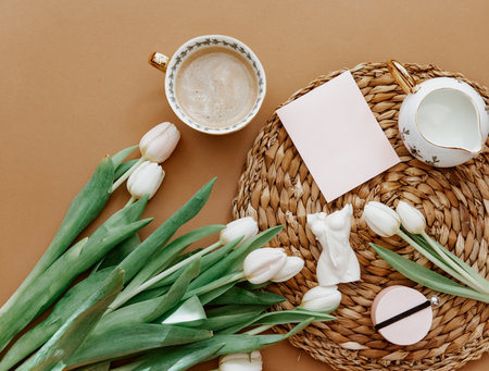 Spring composition. White tulips, coffee cup, candle on brown background. Mother day, March 8. Blank greeting card. Flat Layの写真素材