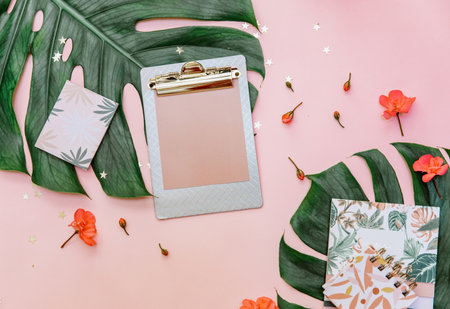 Feminine flat lay, mock up clipboard on tropical pink background for bloggers, modern home office desk with pastel pink, coffee cup, and stationery.の写真素材