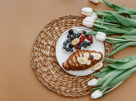 Mothers Day, 8 March, Good morning. White Fresh Tulips, Coffee cup and croissant on brown background, top view, flat layの写真素材