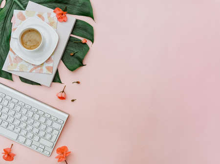 Freelancer home office desk workspace with keyboard and coffee cup on pink background. Flat lay, top view still life conceptの写真素材