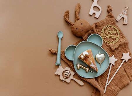 Flat lay minimal Baby birthday concept. Top view composition with newborn accessories, birthday cake, wooden toys on brown background.の写真素材