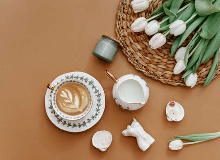 Easter, spring, 8 march, mother day, still life scene. White tulips and coffee cup on brown background, top view, flat lay, copy spaceの写真素材