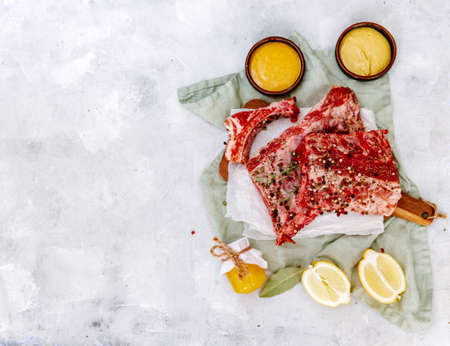 Raw beef ribs, fresh meat with mustard sauce and lemon, top view, flat lay, copy spaceの写真素材
