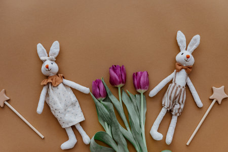 Two rabbits, rainbow and tulips on brown background. Top view, flat layの写真素材