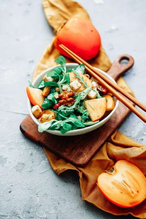 Healthy salad with persimmon, arugula, nuts and feta cheese. Fitness food. Superfoods Vitamin autumn persimmon salad.の写真素材