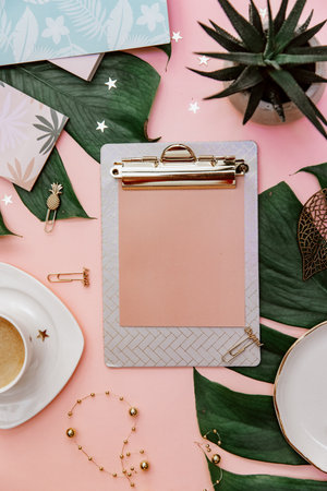 Office table desk. Tropical Flat lay. Home office workspace. Coffee cup and monstera leaf on pink background.の写真素材