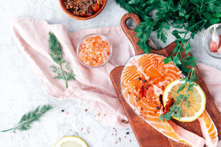 Slices of red fish with rosemary branch, on the cutting board. Cooking process.の写真素材