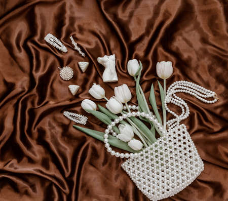 Flat lay fashion composition with white tulips, pearl bag, perfume bottle and women's accessories...